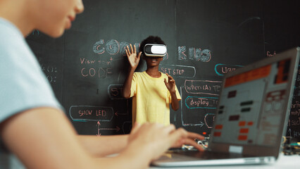 Closeup of school girl hand coding program while african student using VR interact with metaworld....