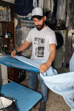 Challenging Stereotypes. Man Ironing Clothes in Local Laundry.