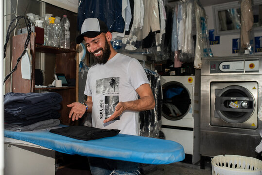 Smiling Middle Eastern Laundry Owner Enjoys His Work.