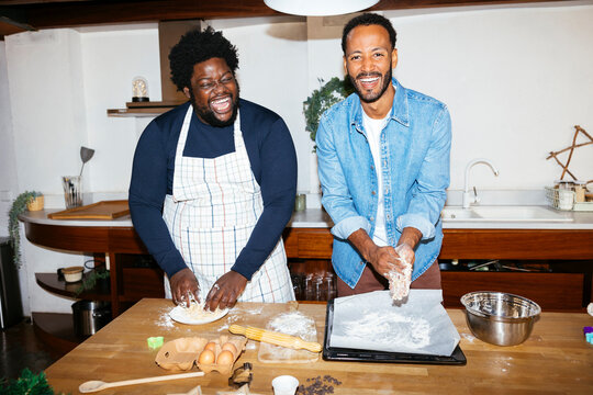 Smiling male friends cooking in kitchen