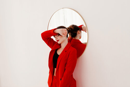 Young stylish female in trendy jacket touching forehead