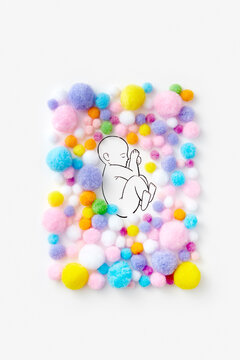 Frame made of colorful pom poms with sketched baby inside