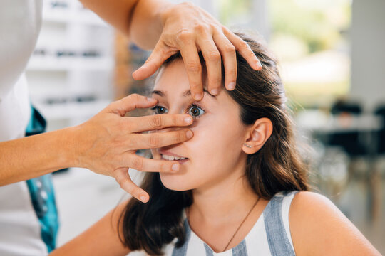 Crop oculist putting contact lenses on a girl