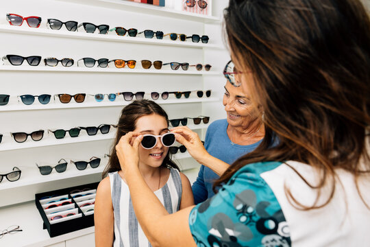 Anonymous doctor trying glasses on smiling young girl