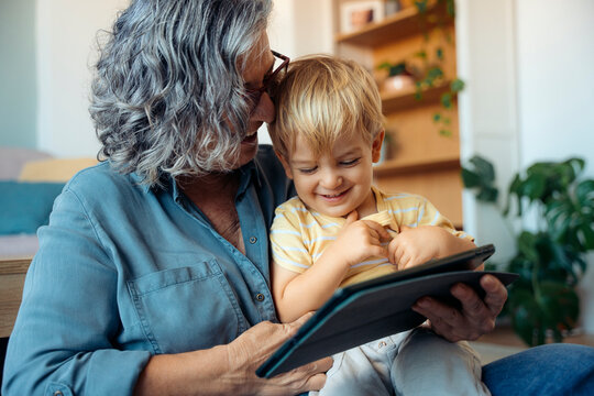 Grandma and grandchild having fun together with tablet device