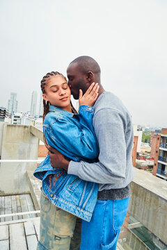 Couple embracing romantically on a rooftop terrace.