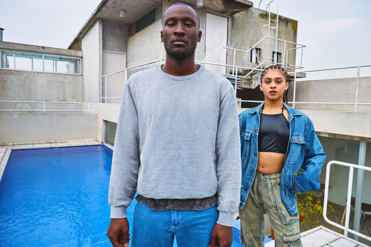 Portrait of a young multiracial male-female friend duo on a terrace.