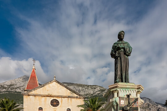 Scenic view of St. Mark church and statue of Haran Narod in Makarska, Split-Dalmatia, Croatia, Europe. Biokovo mountain range in background, Dinaric Alps. Travel destination in summer. Adriatic sea