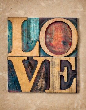 Love word in vintage old wood type. Vertical image. Wooden background.