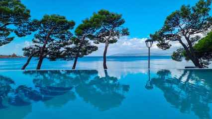 Infinity pool in luxury hotel along the promenade in coastal town Makarska, Split-Dalmatia, Croatia, Europe. Coastline of Makarska Riviera, Adriatic Sea. Dreamlike atmosphere. Vacation summer concept