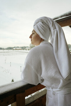 A woman in a bathrobe and a towel on her head outside at winter