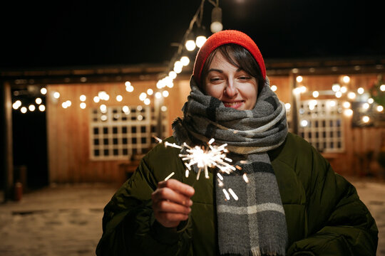 A woman stands in the evening with a sparkler in her hands
