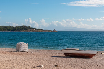 Old wooden boat on the beach with scenic view of lighthouse Svjetionik Sveti Petar in port of...