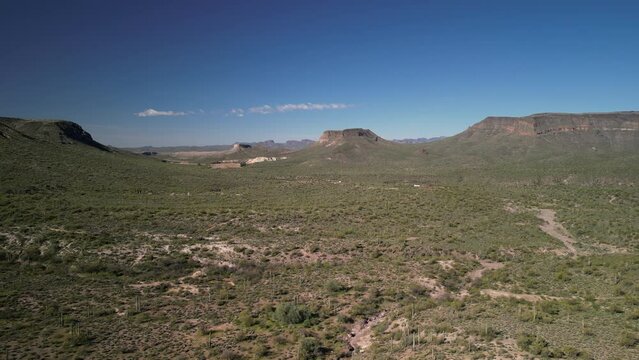 Aerial backing away from desert hills and cliffs in north Phoenix Arizona green desert