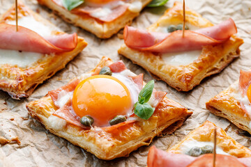 Puff pastry egg and ham mini tarts, focus on the tart with egg, close up view. Delicious breakfast or Easter snack