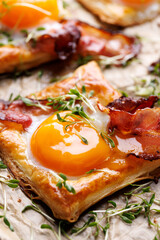 Puff pastry egg and bacon mini tart sprinkle fresh cress, close up view. Delicious breakfast or Easter snack
