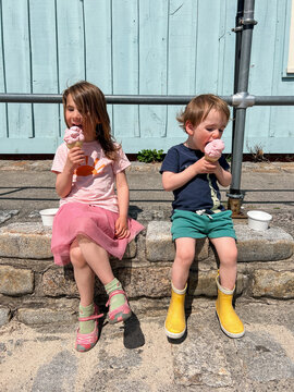 Two Kids Eating Ice Cream Cones Outside the Ice Cream Shop
