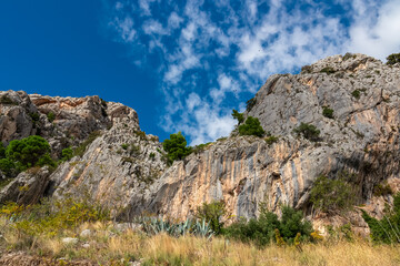 Idyllic hiking trail along coastline of Makarska Riviera in coastal village Kotisina, Split-Dalmatia, Croatia, Europe. Massive rock formation cliffs in Biokovo nature park. Mountains of Dinaric Alps