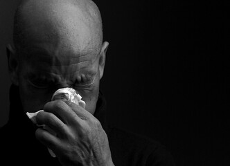 catching the cold and flu man blowing nose after catching a cold with grey background with people stock photo	