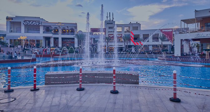 Cairo festival city mall food court in New Cairo, Egypt daylight exterior view showing fountain , restaurants , coffee shops, people and clouds in sky in background