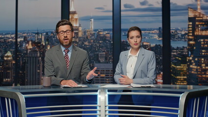 Positive news readers talking live tv newscast in night channel studio closeup