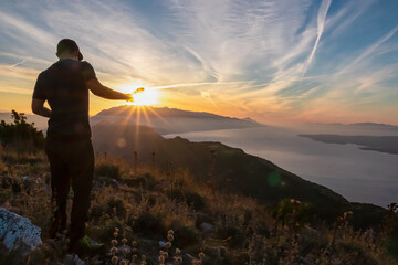 Fototapeta premium Hiker man with scenic sunrise view from top of mount Kula near Omis, Dinara mountains, Split-Dalmatia, Croatia, Europe. Coastline of Makarska Riviera, Adriatic Sea. Balkans in summer. Biokovo mountain