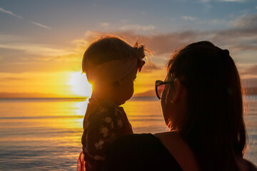 Mother with small child enjoying romantic sunset at beach in town Makarska, Split-Dalmatia,...