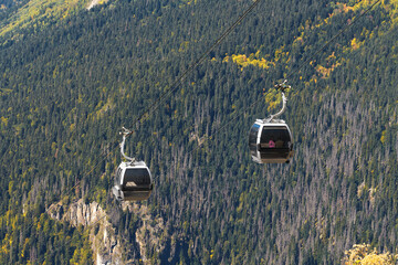 Two oncoming cable car gondolas at altitude on the background of picturesque Dombai autumn...