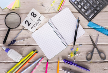 March calendar with number  28. Copy of space note. Top view of blank notepad. Space for text in a checkered sheet, stationery background with accessories.