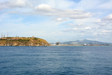 Fototapeta na wymiar View from the sea of the port and coastal infrastructure against the background of the blue sky