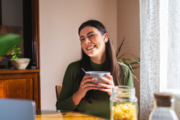 A young woman eating corn flakes for breakfast in the morning in her apartment	