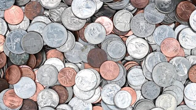 4K HD video panning down dirty American coins laying on a flat surface. Quarters, dimes, nickels and pennies.
