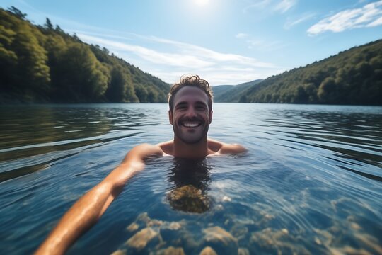 Selfie image of a happy man swim in the lake in middle of beautiful natural landscape
