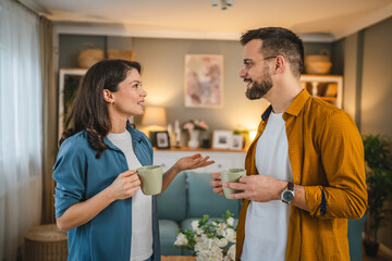 Couple husband wife stand at home with cup of coffee talk happy smile