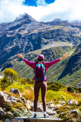 happy backpacker spreads arms enjoying the panorama of otira valley in new zealand