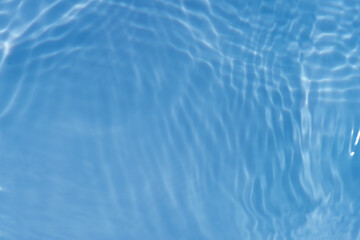 Bluewater waves on the surface ripples blurred. Defocus blurred transparent blue colored clear calm water surface texture with splash and bubbles. Water waves with shining pattern texture background.