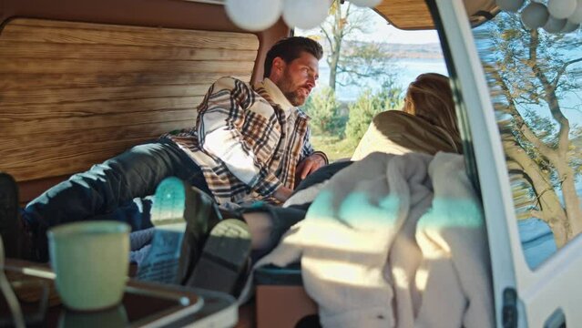 Inside a camper van, a couple sipping warm beverages and engaging in lighthearted conversation.