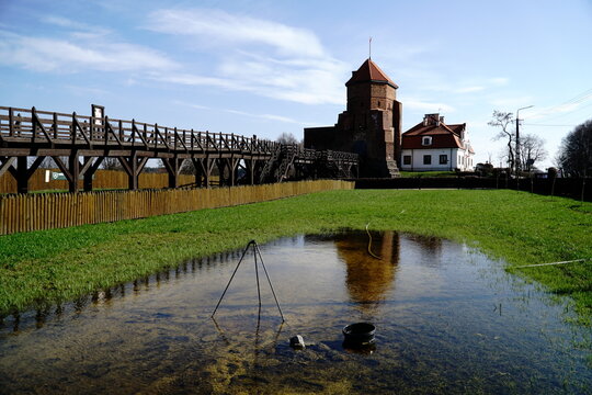 Liw, Poland - March 10th, 2024 - Gothic medieval castle and wooden footbridge and water on field
