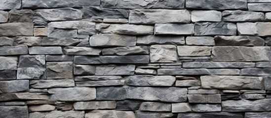 Obraz premium A detailed closeup of a grey stone wall made up of rectangular bricks. The intricate brickwork creates a beautiful pattern in this composite material building material
