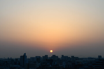 Fototapeta na wymiar 都市の夜明け。神戸市内から芦屋のビルがをのぞみ、ビルの上から朝日が昇る。
