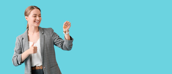 Real estate agent with key from house showing thumb-up on blue background