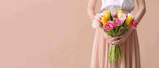 Young woman with bouquet of beautiful tulips on brown background