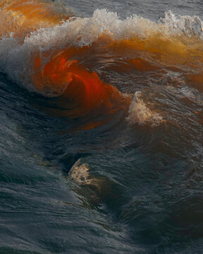 A red wave breaking into the shore in the sunsent