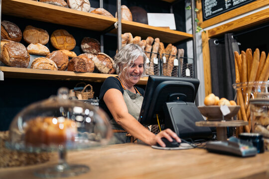 Portrait of woman bakery owner standing using computer inside th