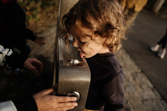 Little boy drinks water from drinking fountain