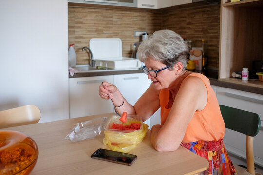 Woman eating watermelon at home wile sitting on the table
