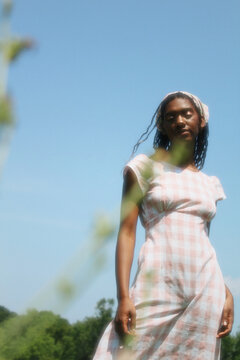 Girl in Gingham Dress in Field with Plant in Focus