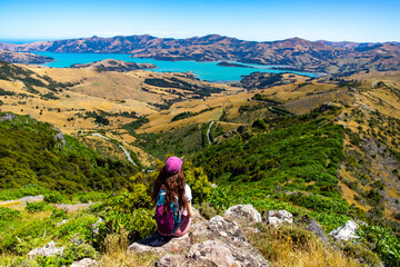 Fototapeta premium hiker girl admires the panorama of akaroa harbour and banks peninsula from the otepatotu scenic reserve, canterbury, new zealand south island near christchurch
