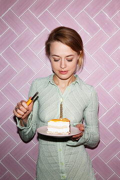 Young woman lighting candle while celebrating birthday