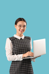 Female Asian teacher with laptop on blue background